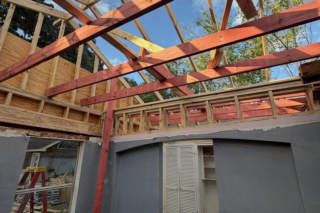 Room opened up to new ceiling framing, with a temporary shoring post, during a ceiling raise in Dallas